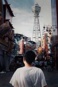 Rear view of man standing on street against buildings