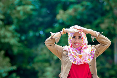 Portrait of young woman standing against plants