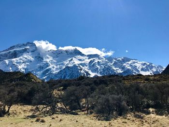 Scenic view of snowcapped mountains against clear blue sky