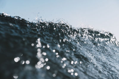 Close-up of water splashing in sea against clear sky