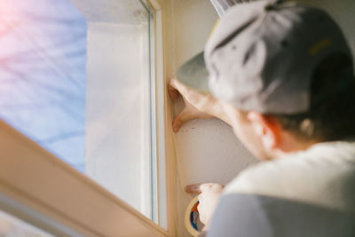 Rear view of boy looking through window at home