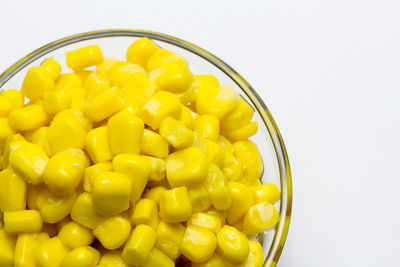 High angle view of yellow eggs in bowl against white background