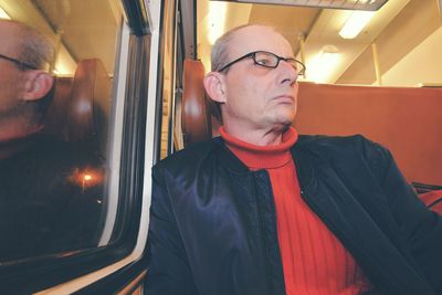 An elderly man in glasses commuting at work. middle age man looking out of the window of train
