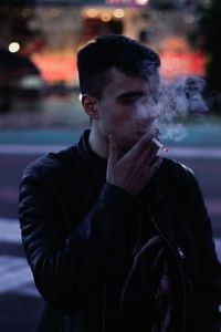 Young man smoking cigarette on road