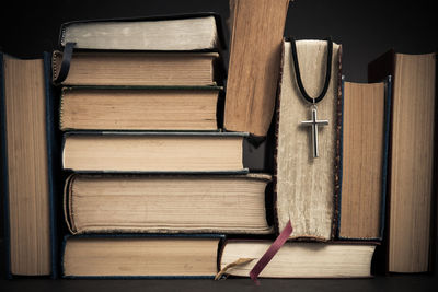 A cross with books on table over the dark background. 