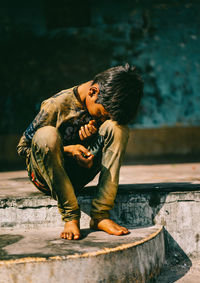 Young man looking away while sitting on wall