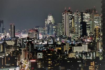 Illuminated cityscape against sky at night