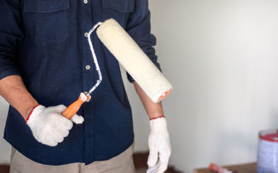 Midsection of man holding paper while standing against wall
