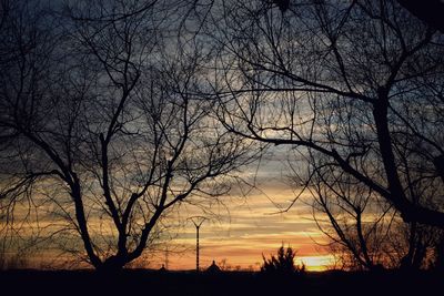 Silhouette bare trees against dramatic sky