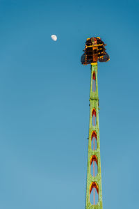 Low angle view of rollercoaster against clear blue sky