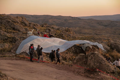 People walking by walking argentina flag on mountain