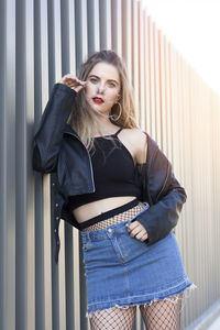 Portrait of beautiful woman standing by wall