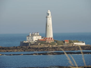 Lighthouse by sea against sky