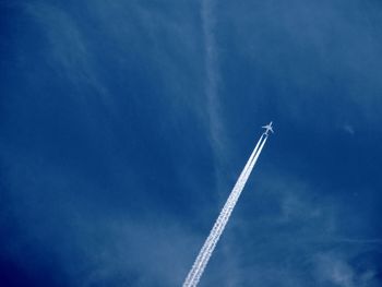 Low angle view of airplane flying against blue sky