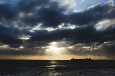 Scenic view of sea against dramatic sky during sunset