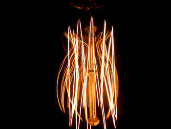 Close-up of illuminated light bulb against black background