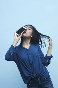 Young woman using mobile phone against blue sky