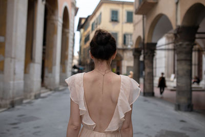 Rear view of woman standing by building in city