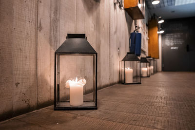 Candle lanterns arranged on floor by wooden wall at hallway in ski resort