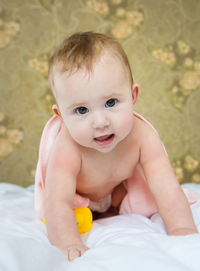 Portrait of cute baby boy lying on bed at home