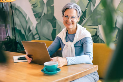 Young woman using laptop while sitting on table
