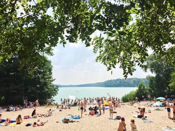 People enjoying on beach against sky