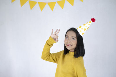 Portrait of smiling young woman standing against yellow wall