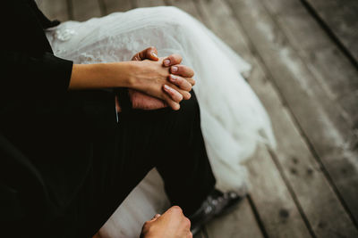 Low section of bride and bridegroom holding hands