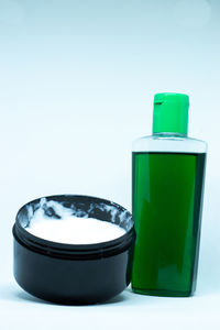 Close-up of green bottle on table against white background