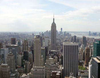 Aerial view of buildings in city against cloudy sky