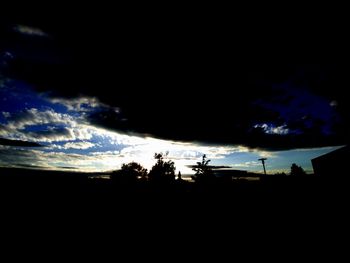 Low angle view of silhouette trees against dramatic sky