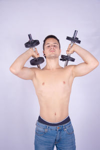 Full length of shirtless man standing against white background