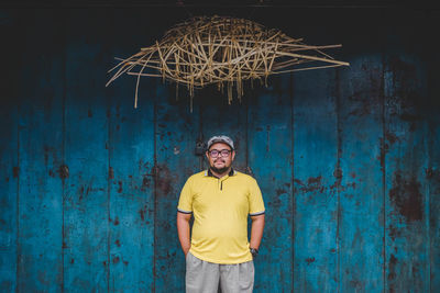 Portrait of young man standing against blue wall