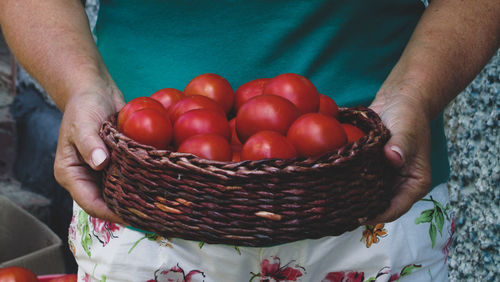 Midsection of man holding tomatoes in wicker basket