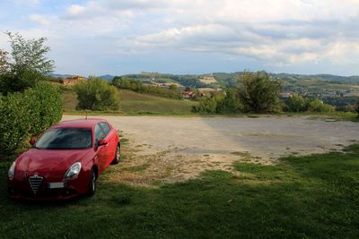 Red car on land against sky