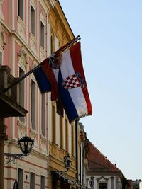 Low angle view of flags hanging on building against sky