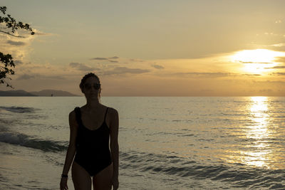 Man standing on beach against sky during sunset