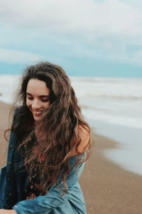 Smiling young woman on beach against sky