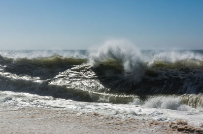 Water splashing in sea against clear sky