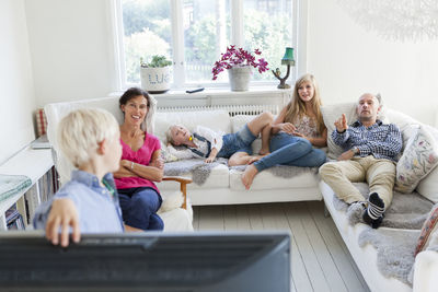 Family with three kids watching tv on sofa