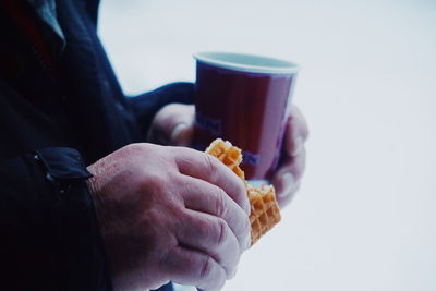 Close-up of man holding drink against white background