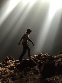 Low angle view of man walking on rock formation at goa jomblang