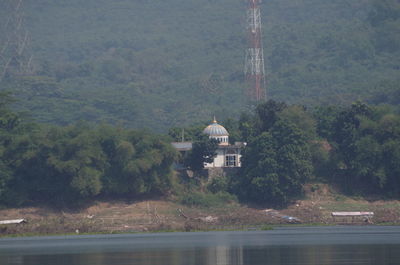 Scenic view of building by trees and mountains