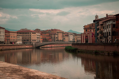 Landscape of river, bridge and buildings of pisa italy on a cloudy day