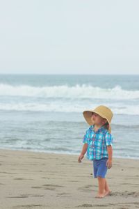 Cute boy walking at sandy beach against sky