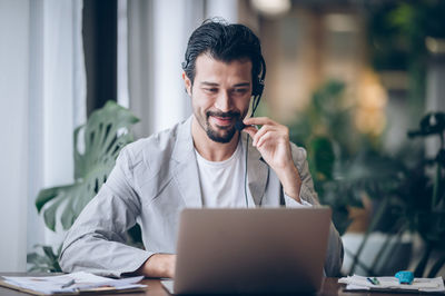 Young man using mobile phone while sitting on table