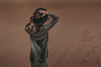 Rear view of woman standing at desert