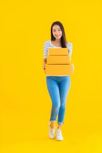 Portrait of a smiling young woman against yellow background