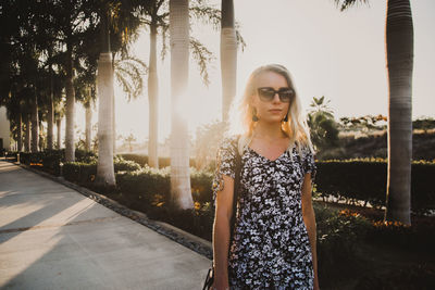 Portrait of young woman standing against trees