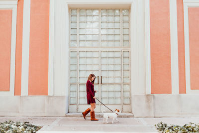 Young woman looking through window on wall